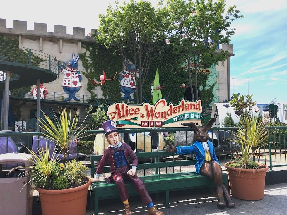 Alice in Wonderland-themed entrance with colorful character statues on a bench.