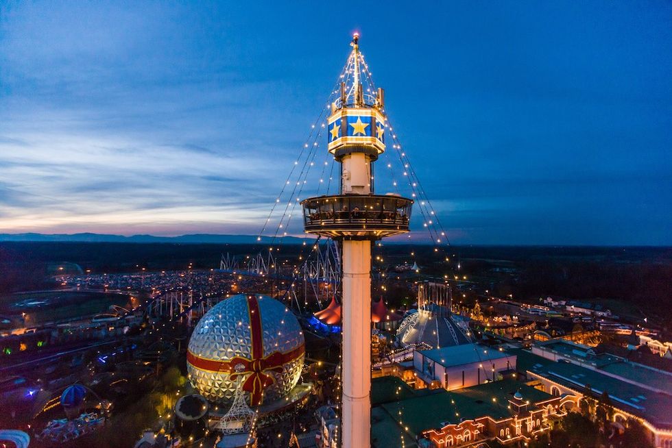 Amusement park at dusk with a tall observation tower and a lit geodesic dome.