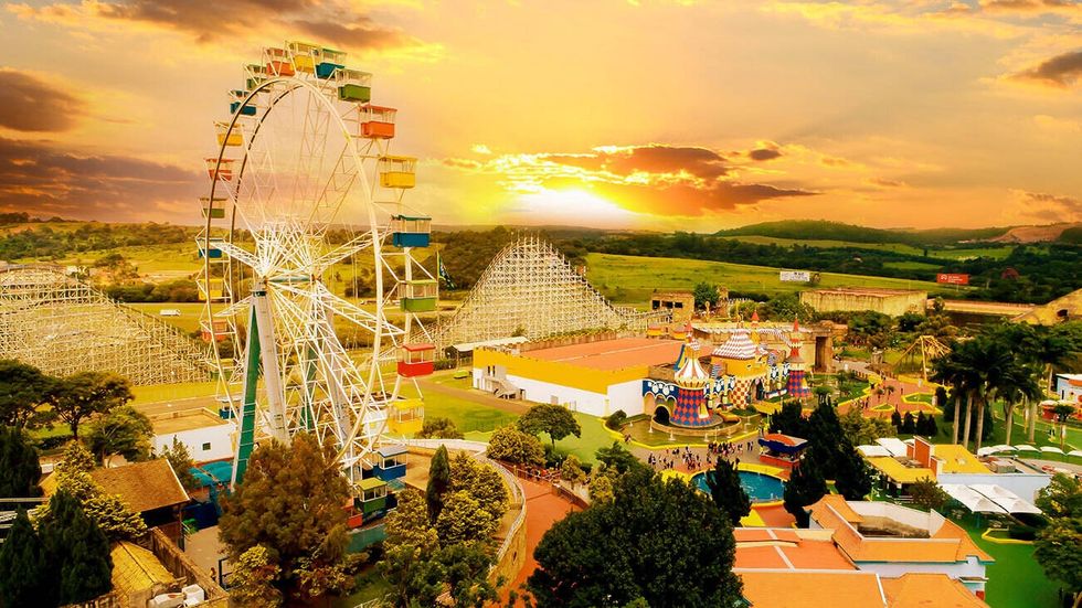 Amusement park called Hopi Hari at sunset with Ferris wheel and colorful buildings.