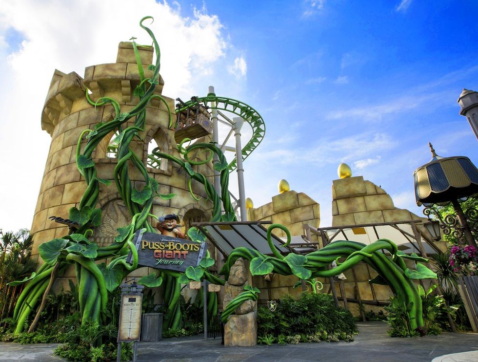 Amusement park ride with giant beanstalks and castle theme under a blue sky.