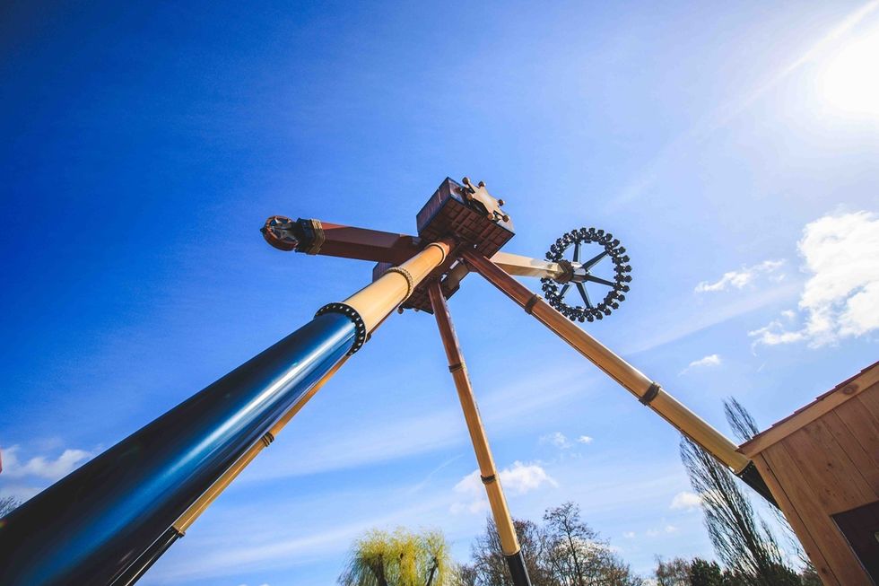 Amusement park ride with long arms against a clear blue sky.