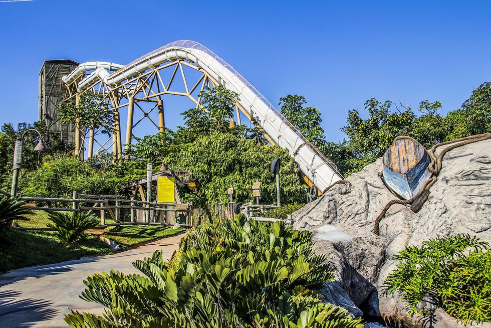 Amusement park water ride with a boat theme, surrounded by greenery under a clear blue sky, at Hot Park Rio Quente