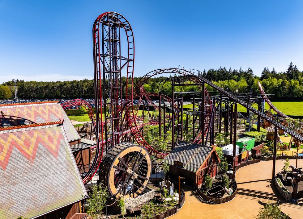 Amusement park with Drakon, a looping red roller coaster under a clear blue sky.