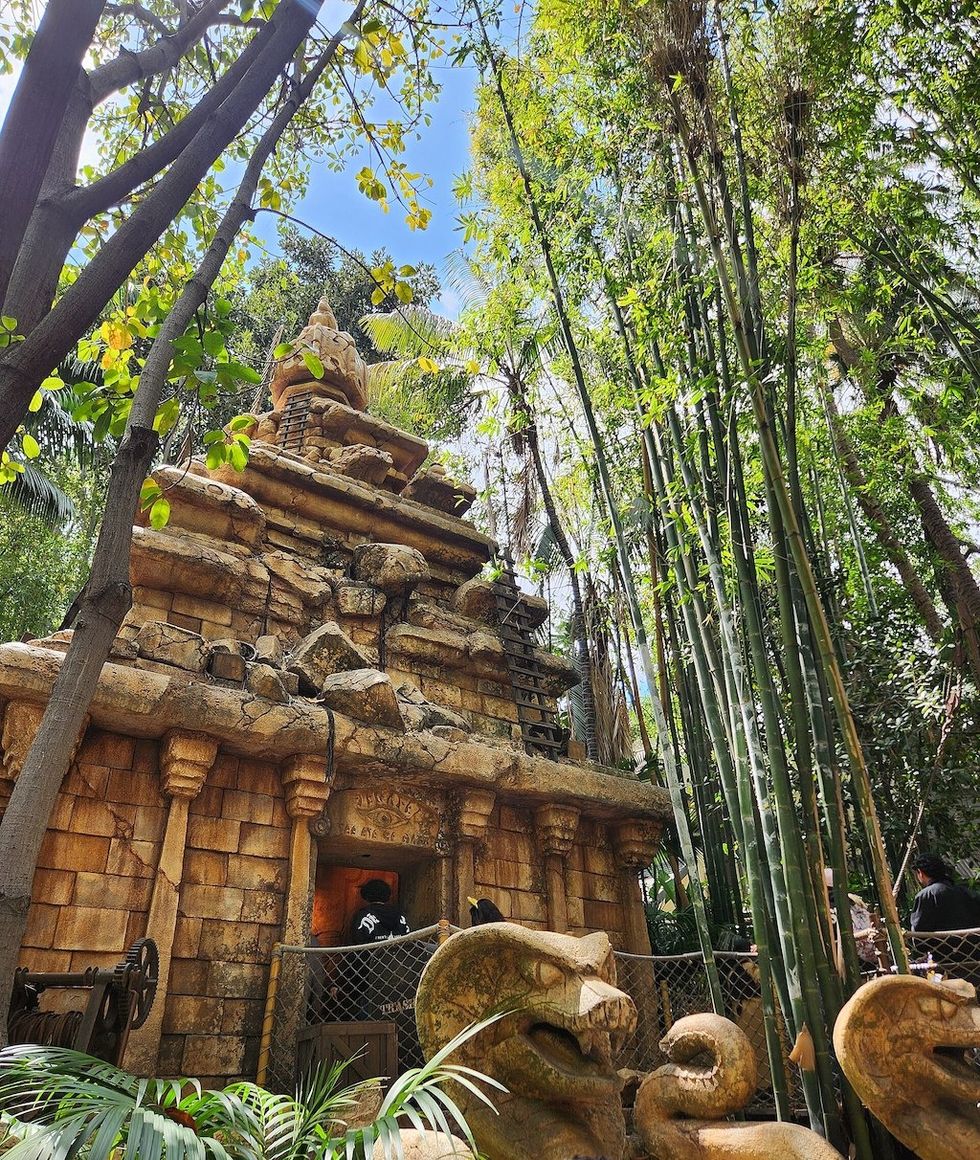 Ancient stone temple surrounded by lush greenery and tall bamboo, Indiana Jones Adventure: Temple of the Forbidden Eye