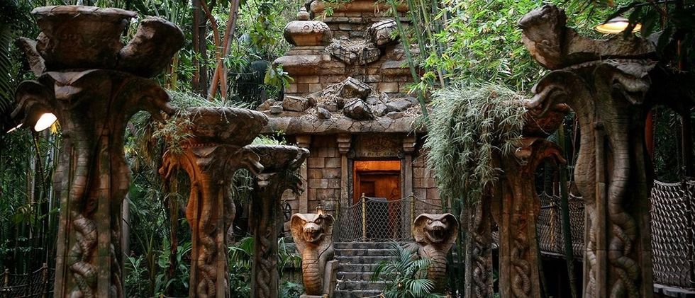 Ancient stone temple with ornate columns surrounded by lush jungle foliage.