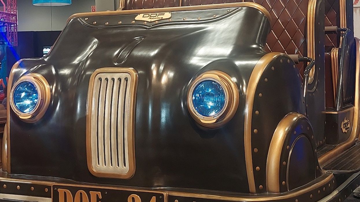 Antique-style car ride with blue headlights and brown leather seats at an indoor exhibition.