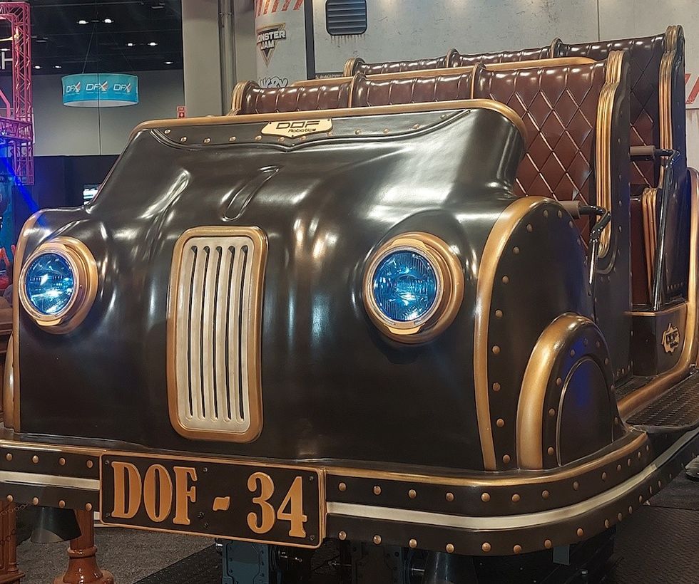 Antique-style car ride with blue headlights and brown leather seats at an indoor exhibition.