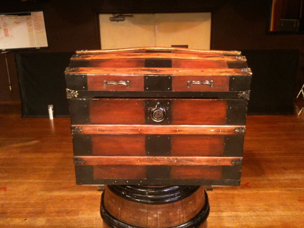 Antique wooden chest with black metal accents on a wooden floor.