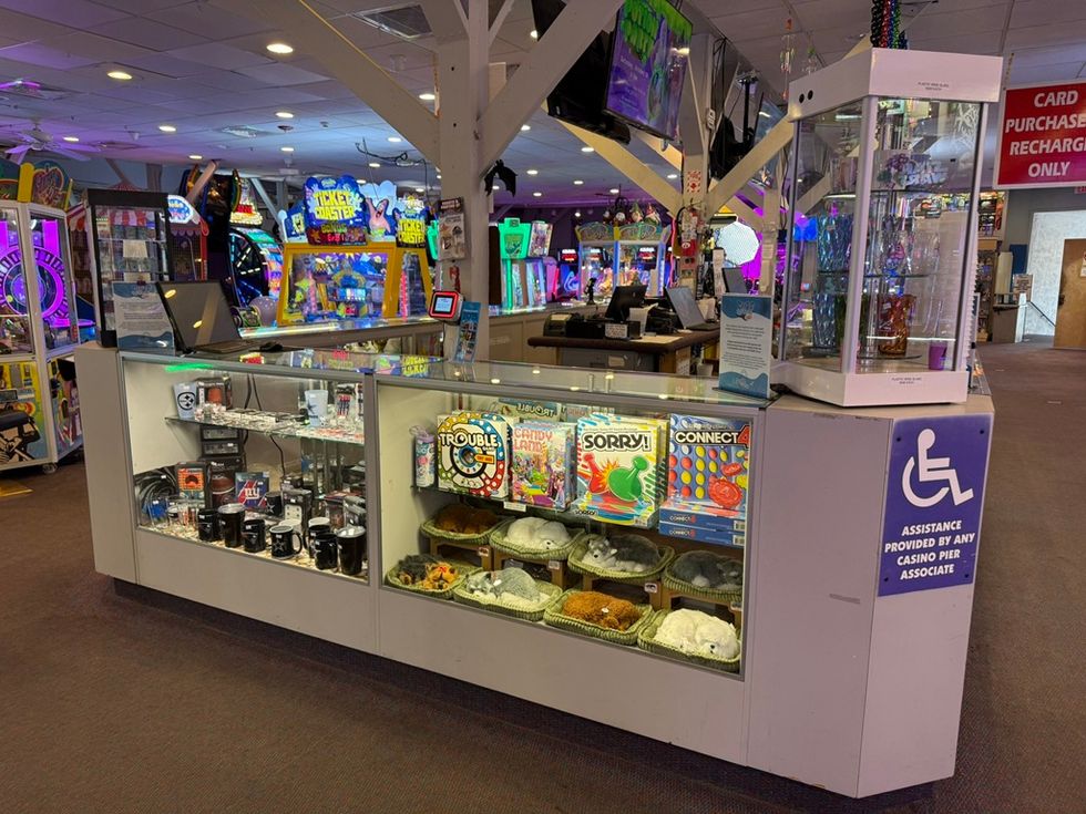 Arcade prize counter with toys, games, and a wheelchair assistance sign.