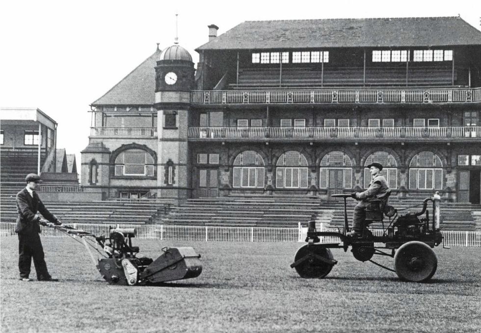 Archive image of two men tending a cricket field with a pavilion in the background.