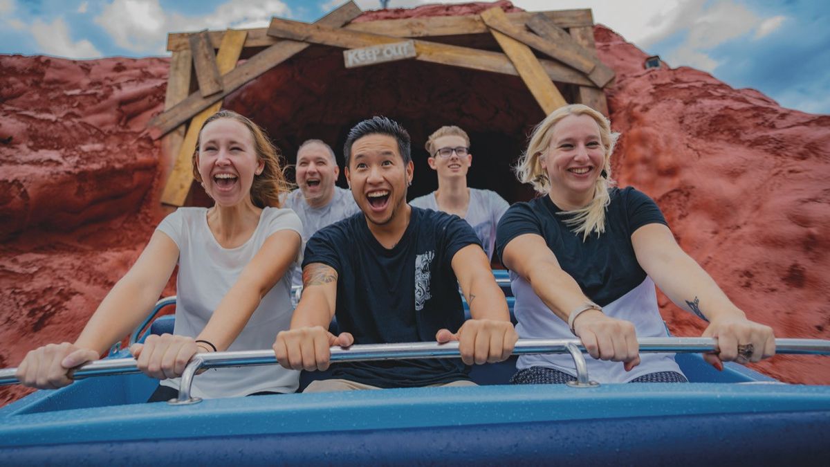 Area 51 water ride at Movie Park Germany. People smiling on a roller coaster, exiting a tunnel with red rock surroundings.