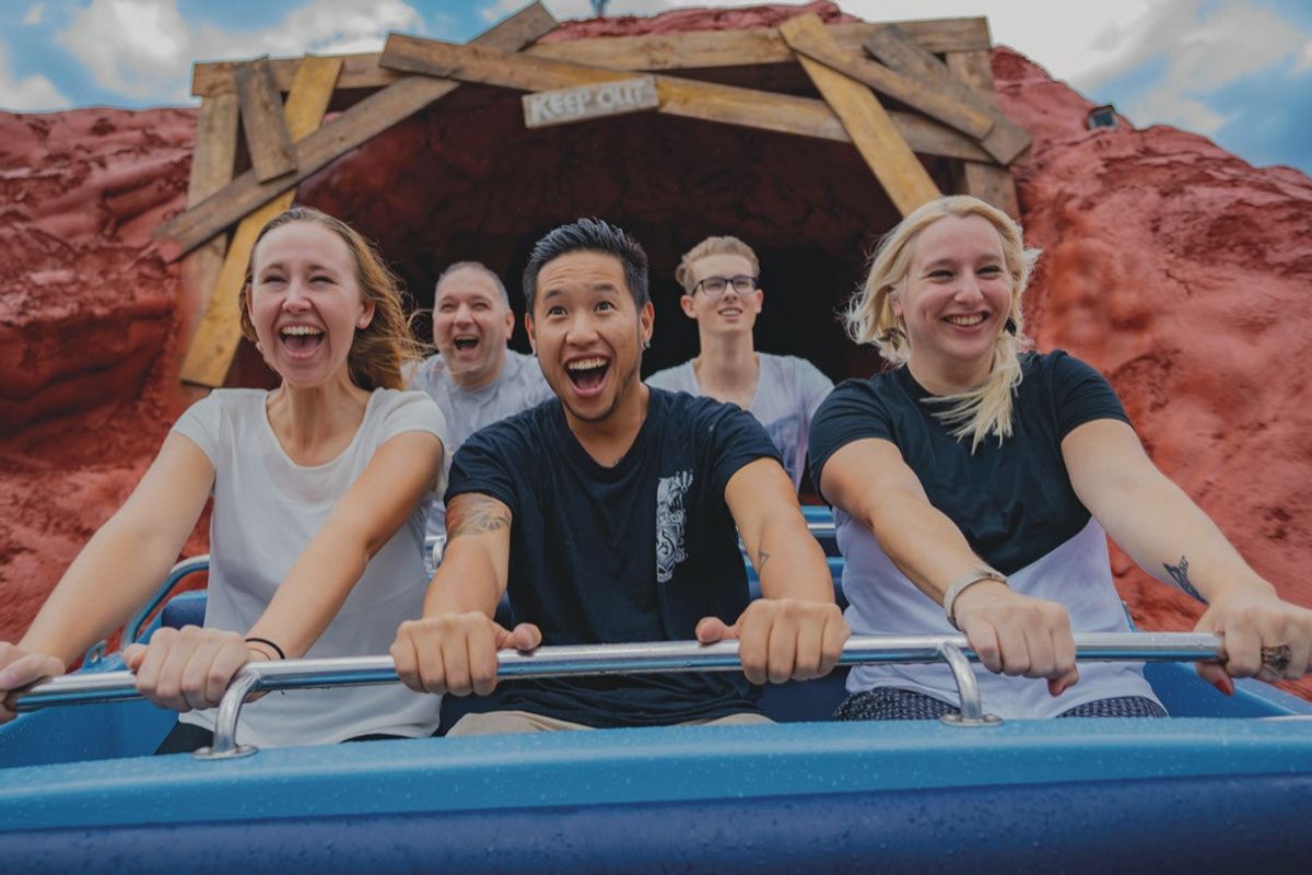 Area 51 water ride at Movie Park Germany. People smiling on a roller coaster, exiting a tunnel with red rock surroundings.