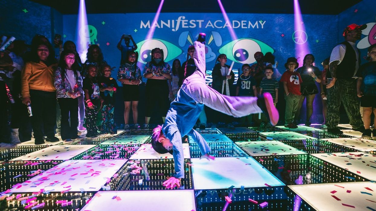 Area15 family rave - Child breakdancing on a lit-up stage, surrounded by a cheering audience.