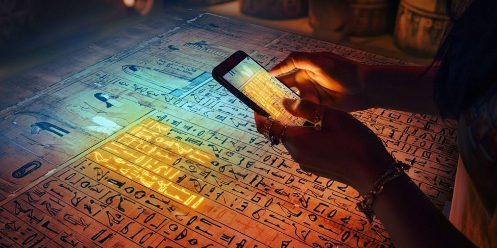 Artist's impression of the British Museum's new immersive exhibition Book of the Dead Journey through the Afterlife exhibition with visitor using device