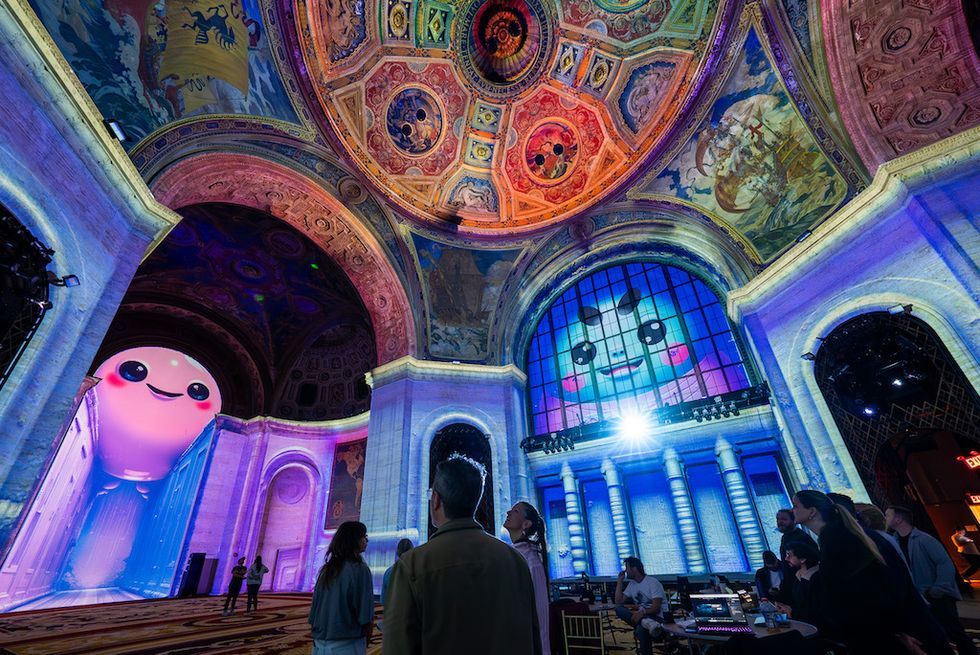 Artistic interior with large animated faces projected on walls and ceiling.