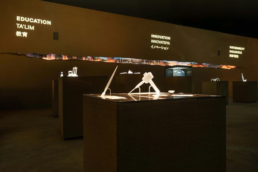 ATELIER BR\u00dcCKNER Uzbekistan Pavilion \u2013 Expo 2025 Osaka Exhibit with lit displays and words "Education", "Innovation", "Sustainability" on the wall.