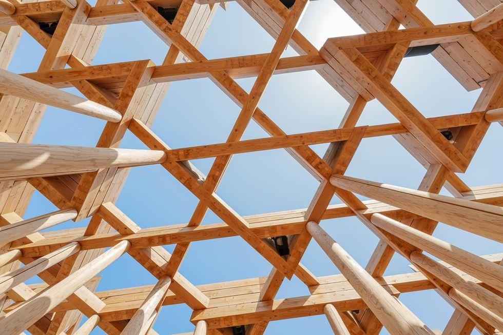 ATELIER BR\u00dcCKNER Uzbekistan Pavilion \u2013 Expo 2025 Osaka Wooden lattice ceiling with beams, against a clear blue sky.