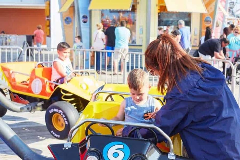 Attendant checking child's seatbelt at Moreys Piers Jump Around Kiddie Ride attraction staffing