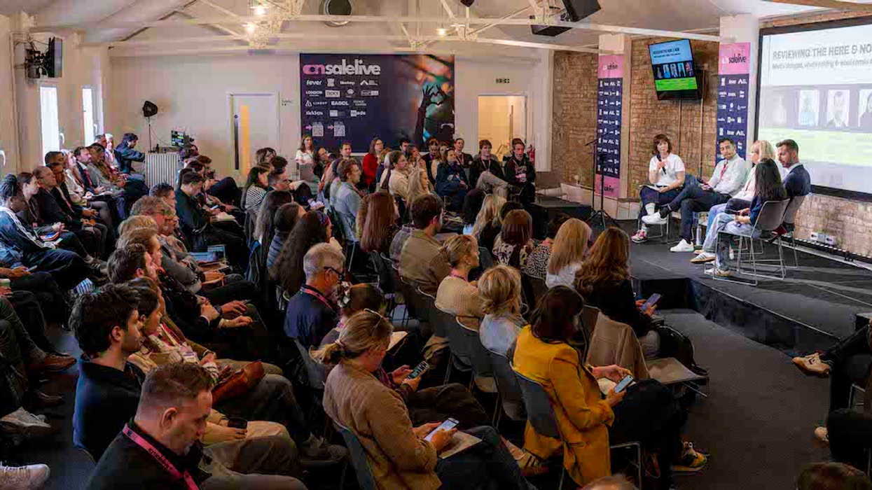 Audience attending a panel discussion at a conference in a brick-walled room.