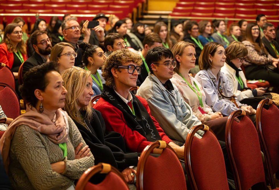 Audience attentively listening at a conference in a theater with red seats.