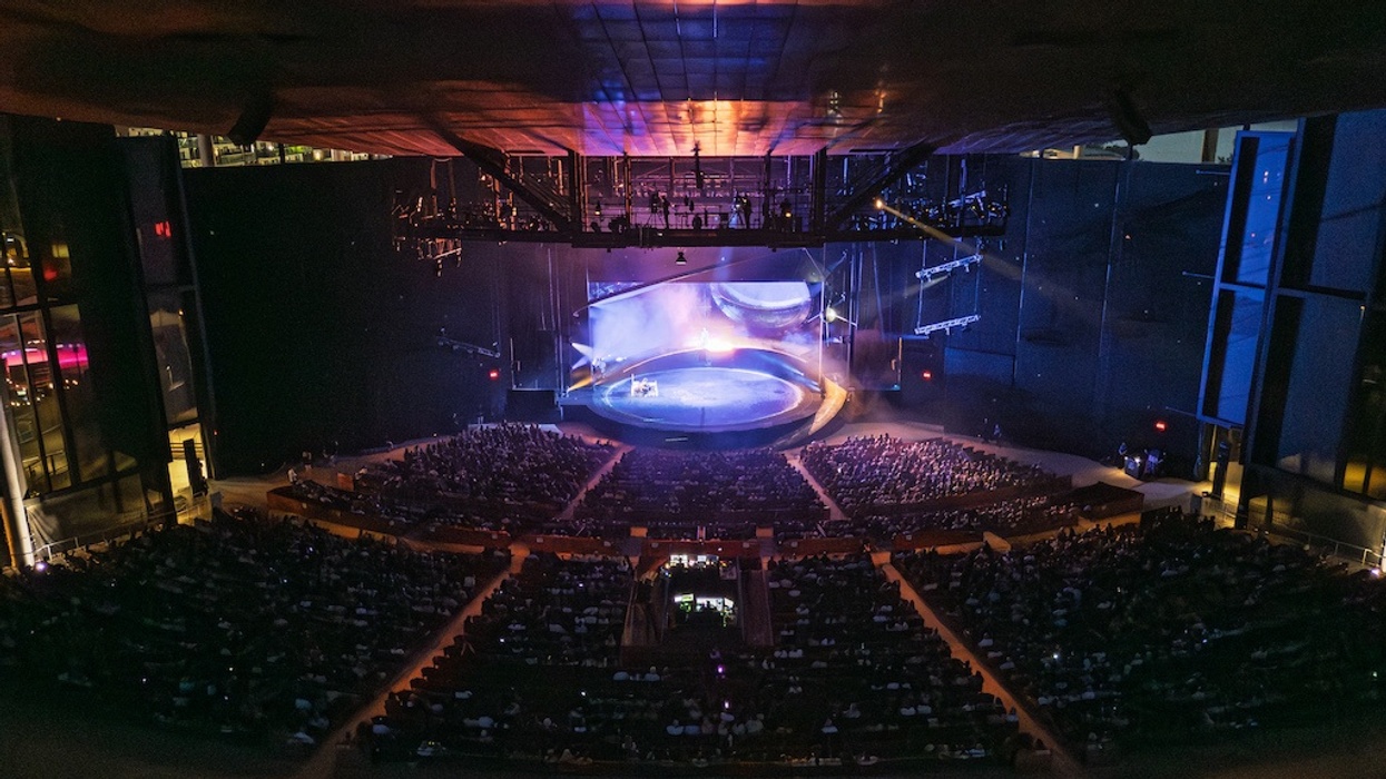 Audience watching a performance in a large indoor theatre, Amphithéâtre Cogeco, with colorful stage lighting.