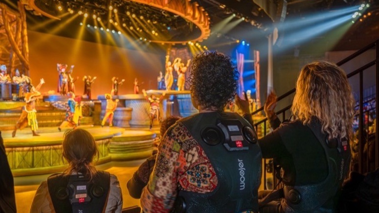 Audience with vibrating vests watches The Lion King: Rhythms of the Pride Lands at Disneyland Paris, a vibrant stage performance with colorful costumes.