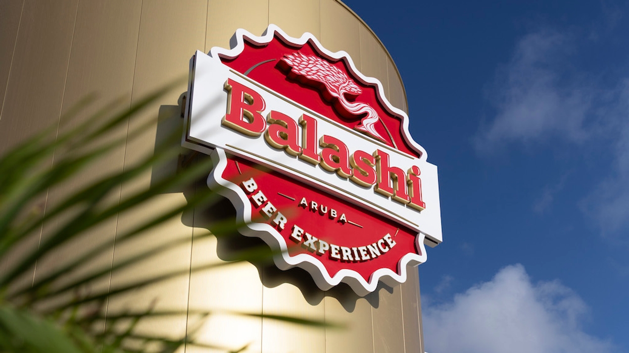 "Balashi Beer Experience sign on gold building with clear blue sky backdrop."