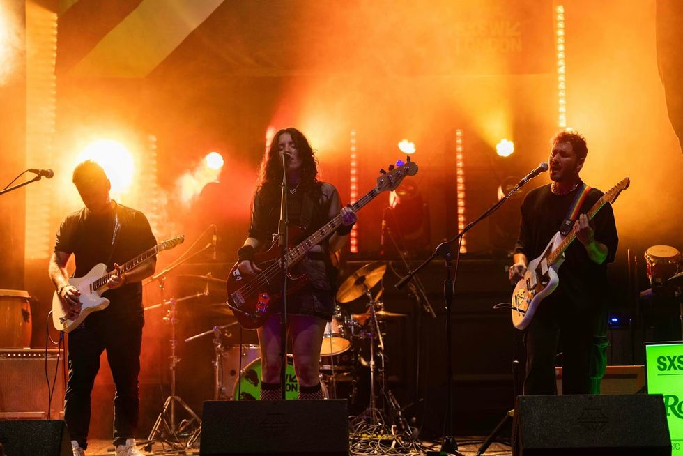 Band performing on stage with vibrant orange backlighting at SXSW London
