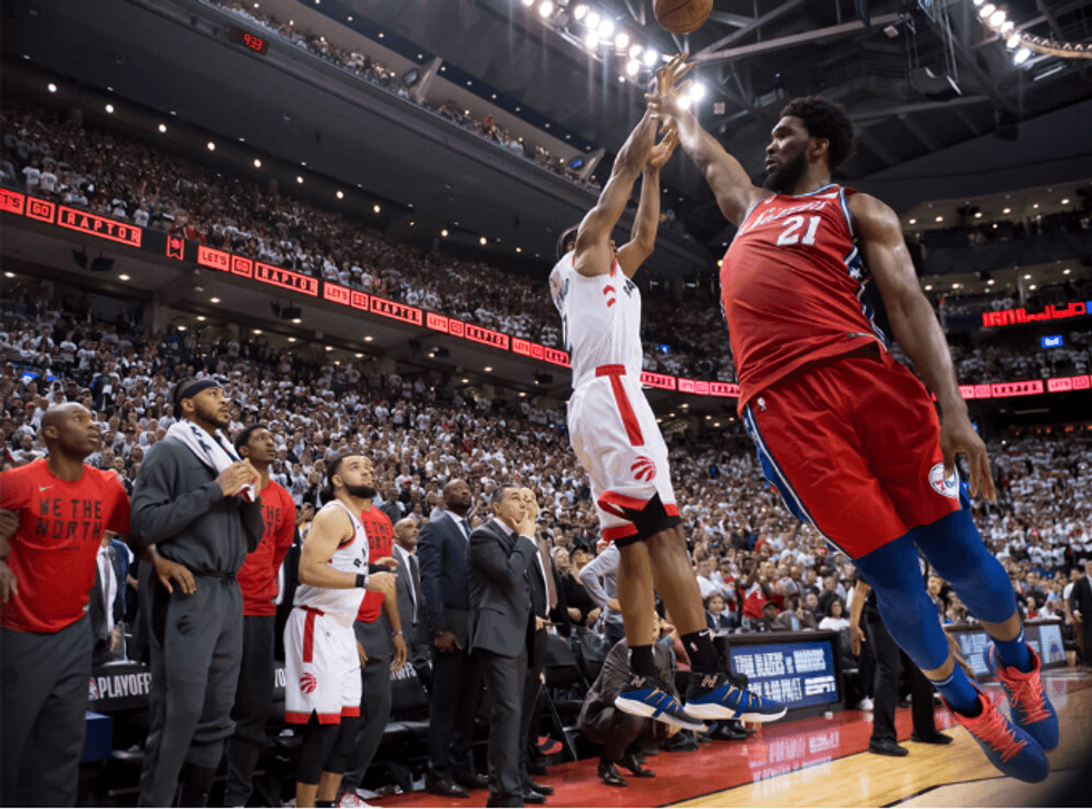 Basketball players in action during an intense game, with a crowded arena background.