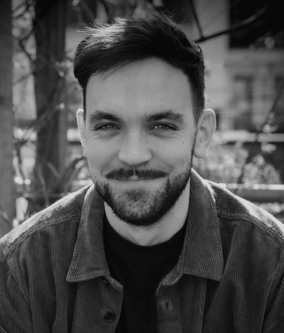 Black and white photo of Mike Hill, a smiling man with a beard, outdoors.