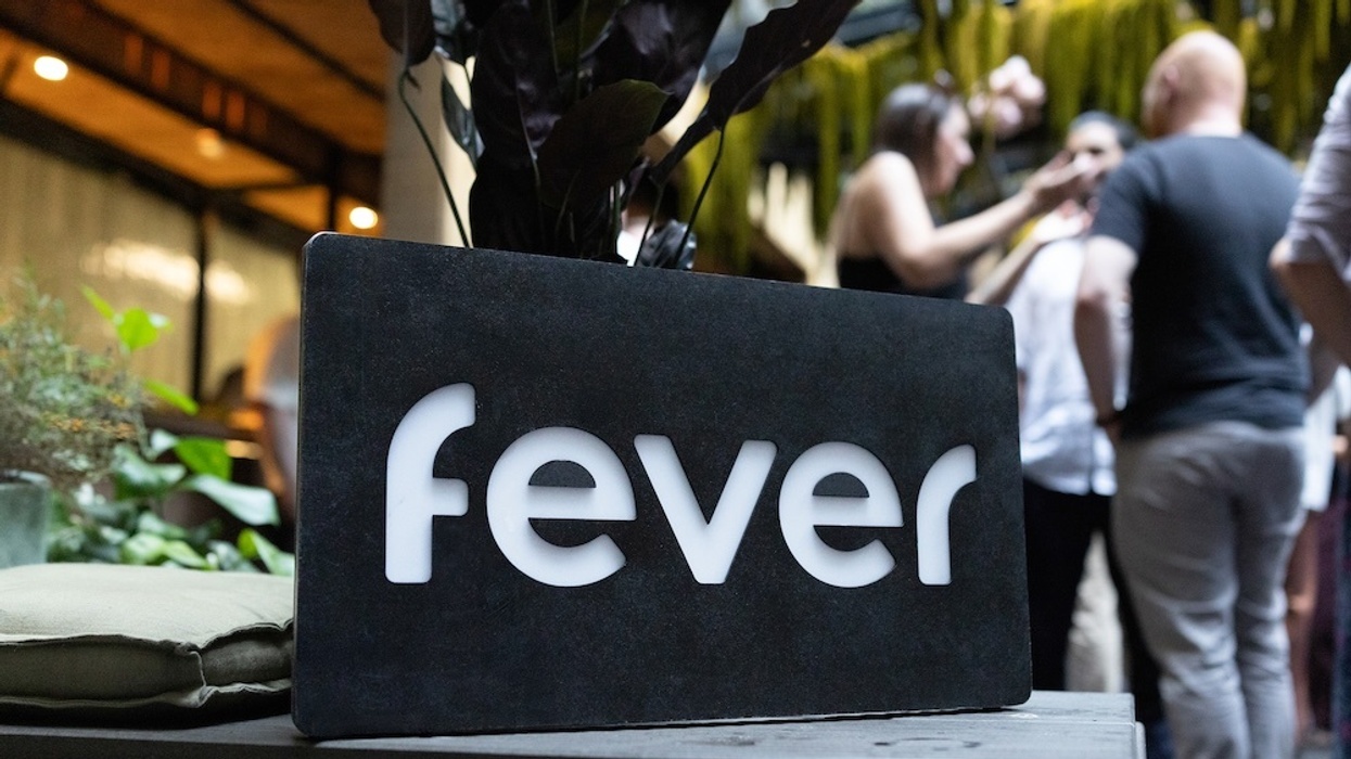 Black sign with "fever" in white; people mingling in the background.