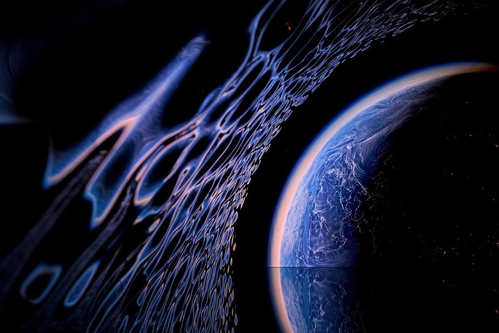 Blue planet with swirling clouds beside abstract curved patterns in space.