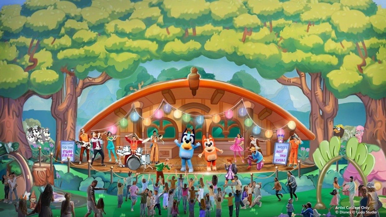 Bluey characters perform on a colorful stage in a lively outdoor fair setting.