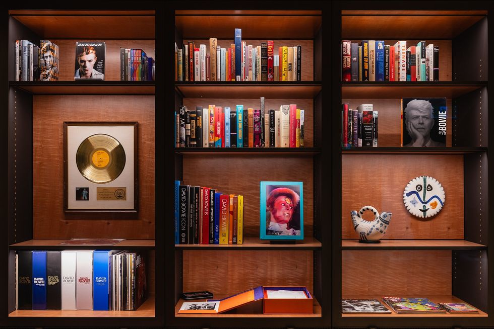Bookshelf with books, records, a gold disc, and decorative art pieces at Mona's library