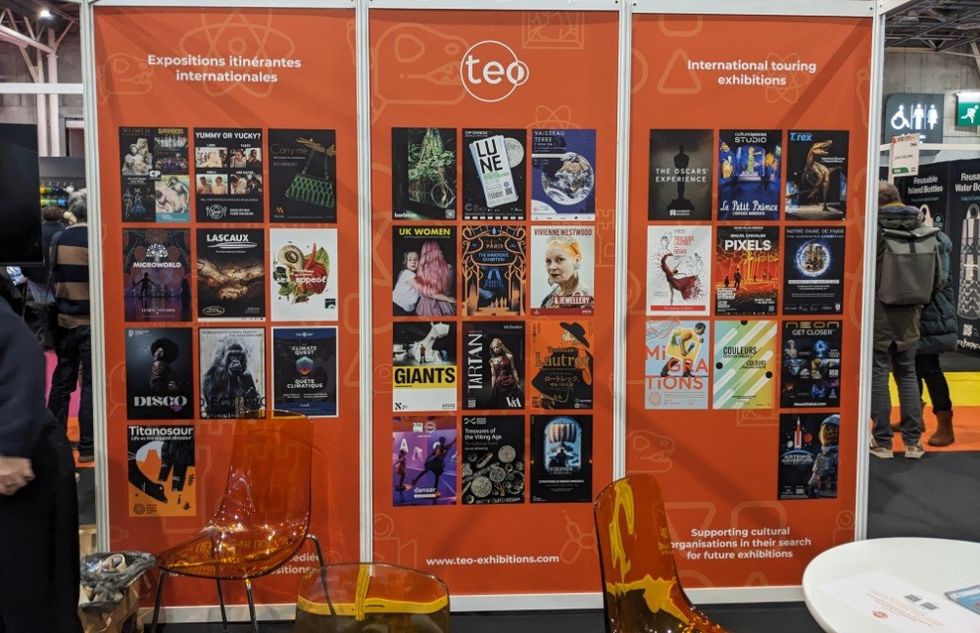 Booth with posters for international touring exhibitions at an event.