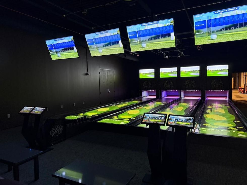 Bowling lanes with digital screens displaying a virtual golf game.