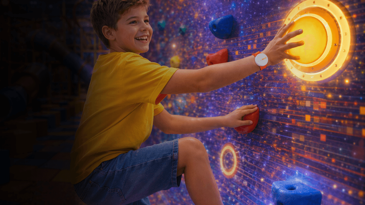Boy climbing a glowing, interactive rock wall lpaying Pico Play's PlayMAXX, smiling in a bright, colorful setting.