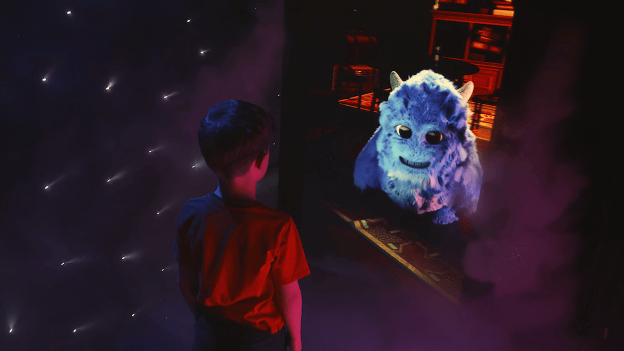 Boy in red shirt looks at a friendly, fluffy blue monster in a glowing, starry space.