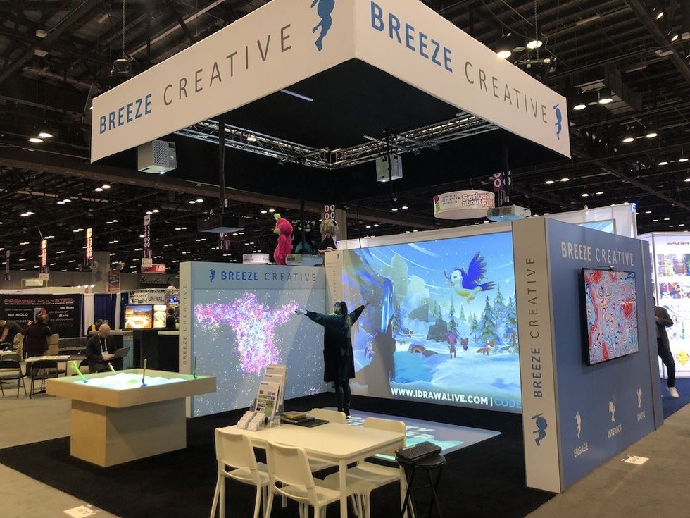 "Breeze Creative exhibition booth with interactive digital displays and seating area."