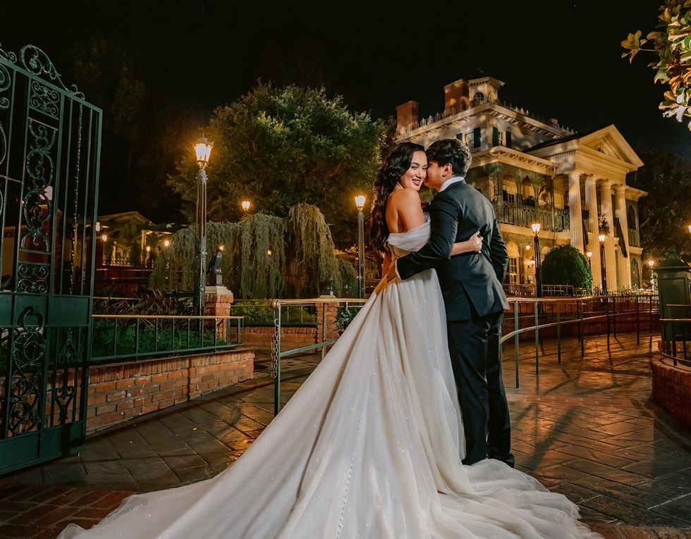 Bride and groom embrace outside Disney's Haunted Mansion at night
