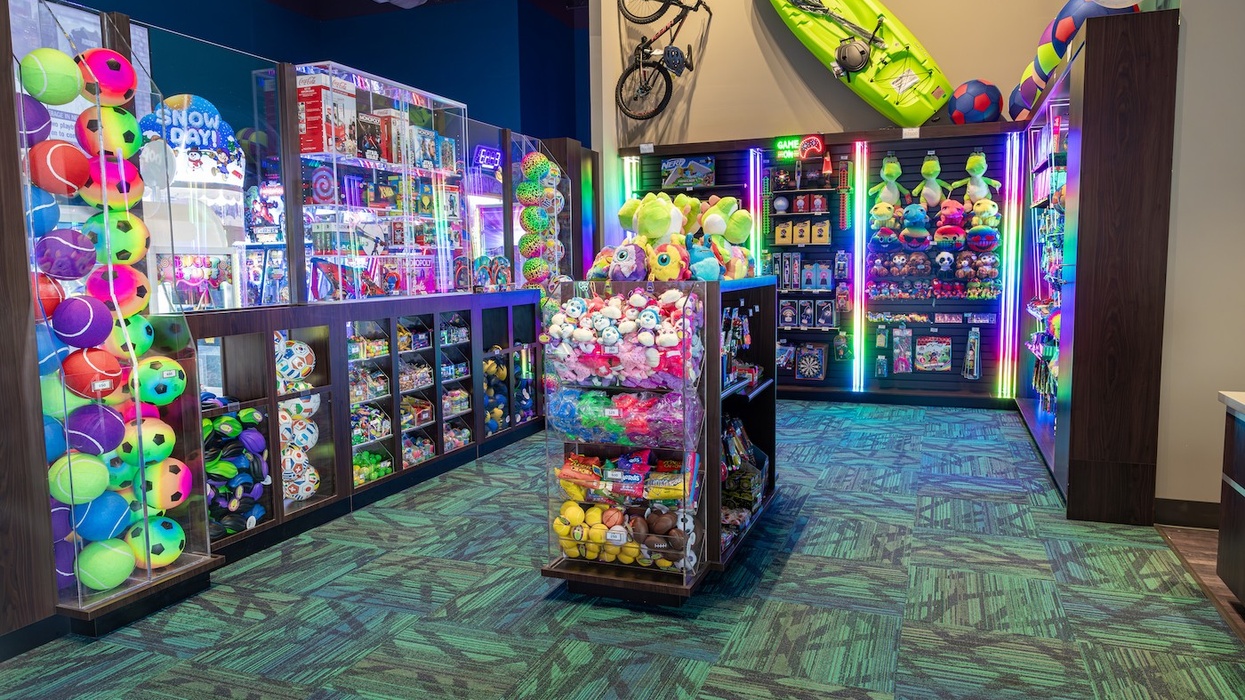 Bright arcade prize area with colorful toys, stuffed animals, and a wall-mounted kayak and bike.