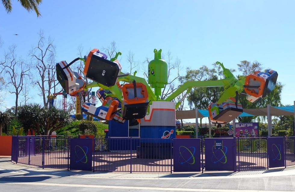 Bright, colorful amusement park ride with green alien and spinning seats.