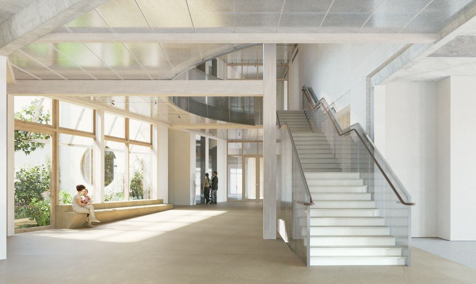 Bright modern atrium with a glass-railed staircase, large windows, and people sitting and standing.