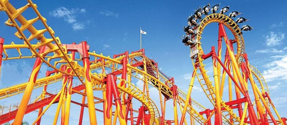 Bright roller coaster with loops against a blue sky.
