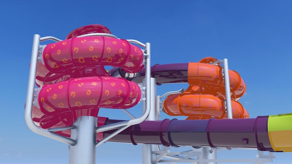 Bright, twisting pink and orange water slides against a clear blue sky.