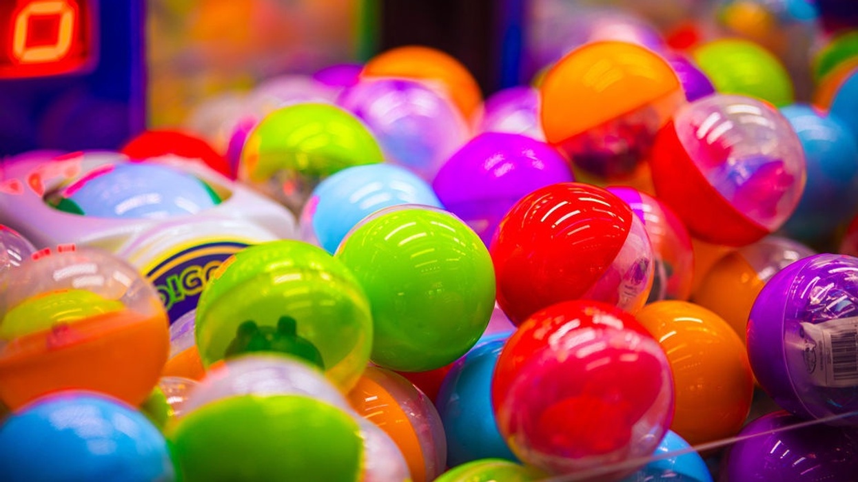 Brightly colored balls in a vending machine, illuminated by a colorful display.