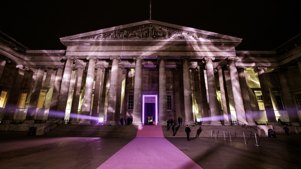 British Museum facade lit with purple lights at night, with a purple carpet leading to the entrance.