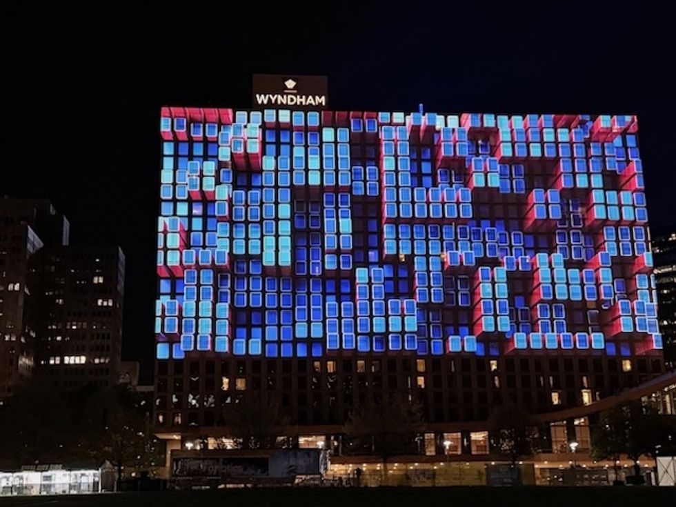 Building facade lit with colorful 3D cube projections at night, under a Wyndham sign.