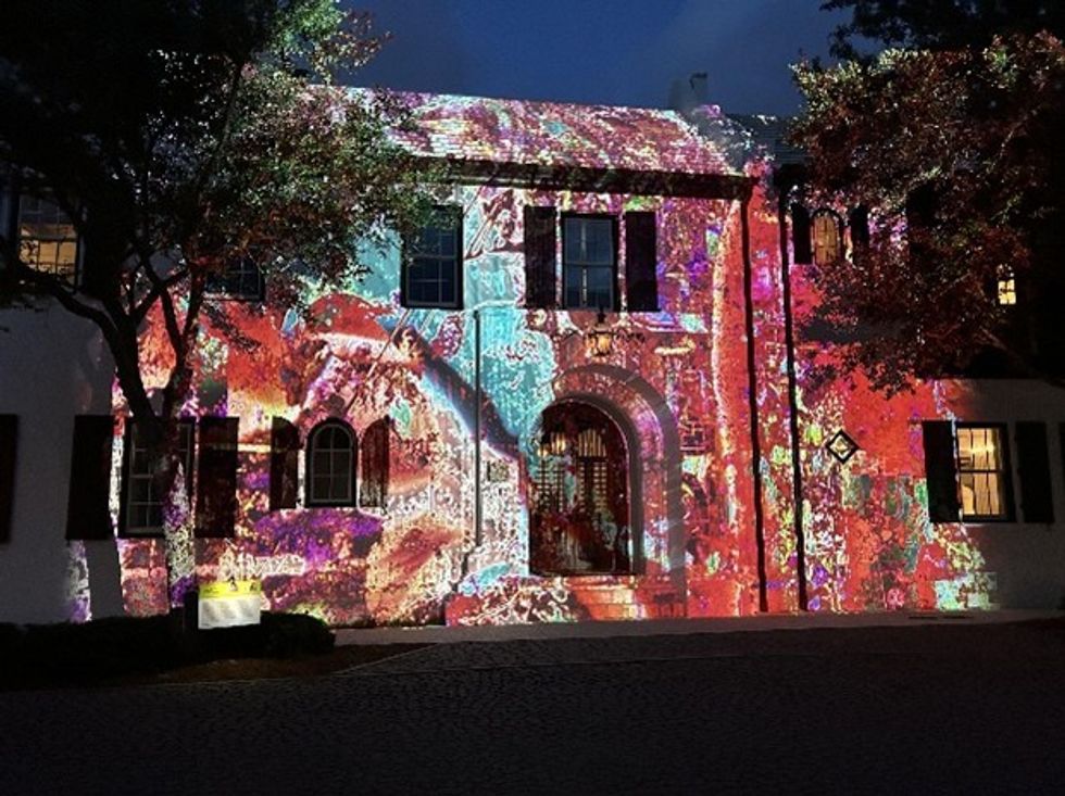 Building facade lit with colorful abstract projections at night.