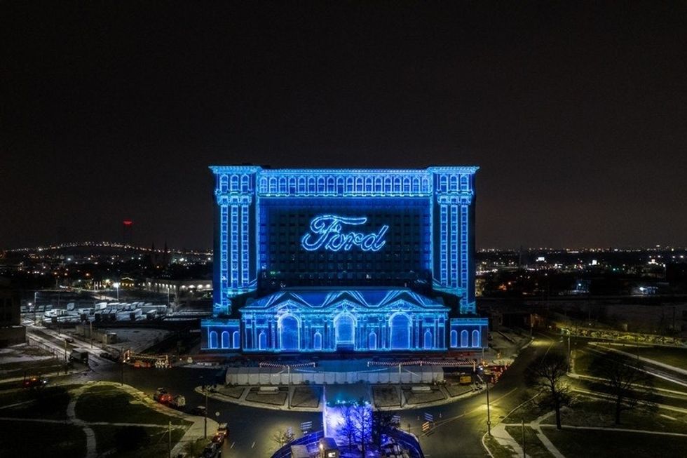 Building lit in blue with "Ford" logo on facade, night view.